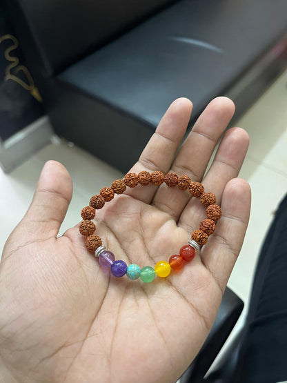 Hand holding a bracelet with multicolored beads on a blurred background