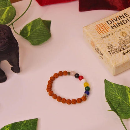Bracelet with colored beads on a white surface with green leaves and a box labeled 'Divine Hindu'.
